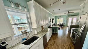 Una cucina con mobili bianchi, un piano di lavoro in marmo e un pavimento in legno.