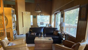 A cozy living room with a leather sofa, two armchairs, a wooden coffee table, and a bookshelf. - Snow! March /April availability! Driveway snow plow included! Dog ok! Fast WiFi! (Homewood)