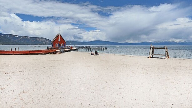 A beach with a red lifeguard tower, a wooden bench, and a pier extending into the water. - Snow! March /April availability! Driveway snow plow included! Dog ok! Fast WiFi! (Homewood)