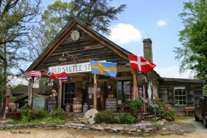 En rustik bygning med et skilt, der siger "COLD SAUTEE ST.". Svenske og danske flag er hængt udenfor.