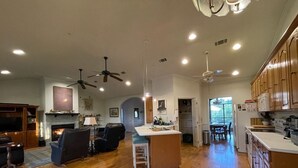 A spacious living area with a fireplace, a dining area, and a kitchen with wooden cabinets and a large island. - Marshbreeze...on Tidal Creek with Marsh View (Darien)