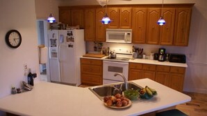 A kitchen with wooden cabinets, a white countertop, a sink, and a fruit bowl. - Marshbreeze...on Tidal Creek with Marsh View (Darien)