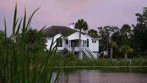 A white house with a balcony and a staircase leading to a dock over water. - Marshbreeze...on Tidal Creek with Marsh View (Darien)