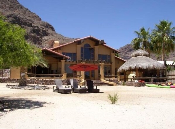 A resort with a large building, outdoor seating, and a thatched-roof structure. - Beach Front Villa - Pets Allowed (Mulege)