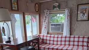 Een gezellige woonkamer met een geruite bank, een houten tafel en een raam met uitzicht op een meer.