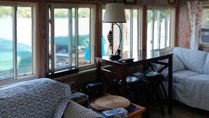 Een gezellige kamer met een bed, een bureau en een lamp. Er zijn ramen met uitzicht op de omgeving.
