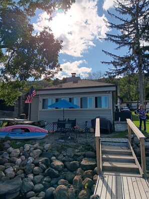 A house with a deck, a kayak, and a fire pit. - Honeoye Lake Waterfront Cottage  (Honeoye)