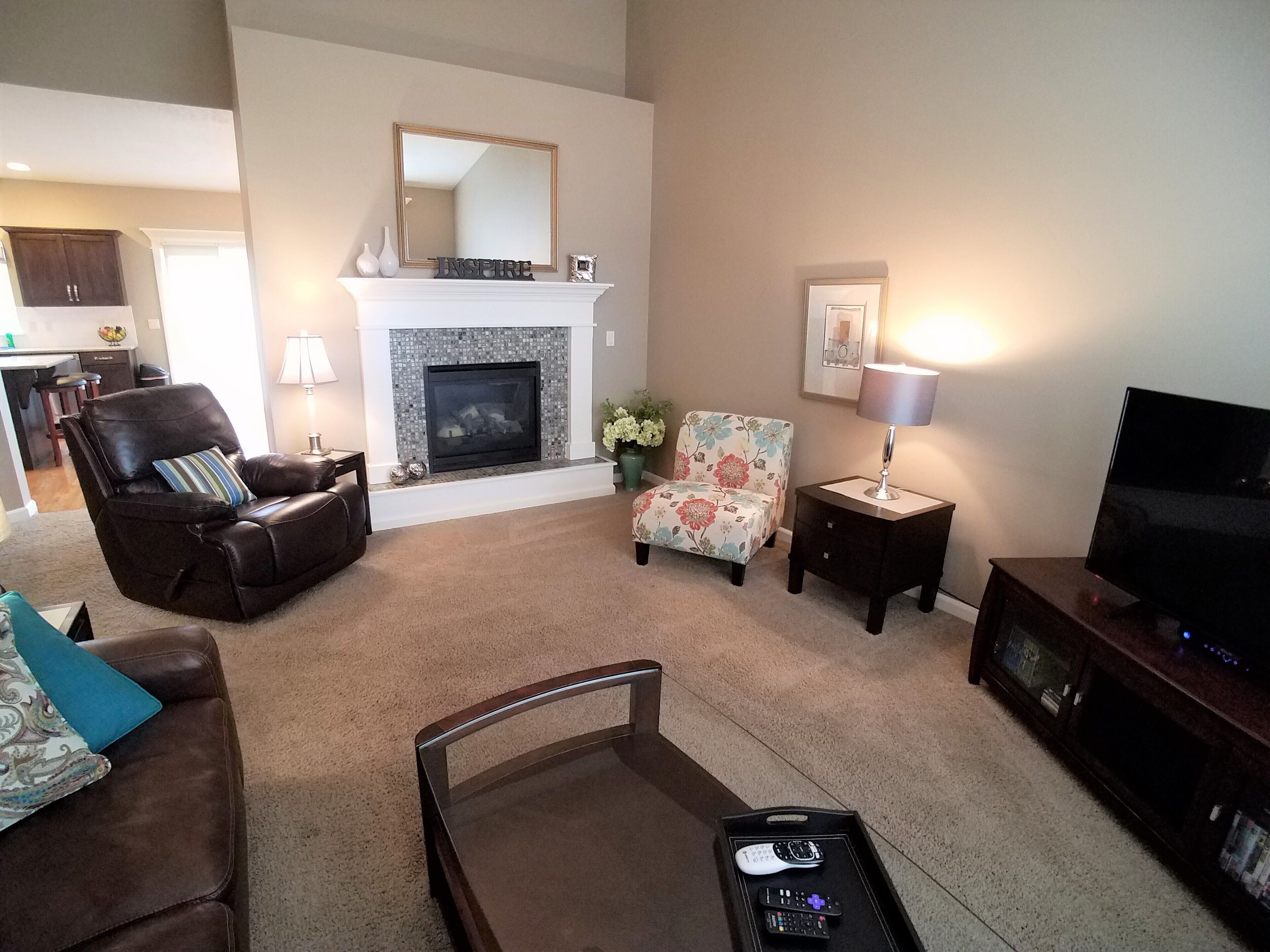 A living room with a fireplace, a sofa, a chair, a TV, and a coffee table.