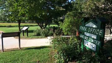 A park office sign with a nature center label, surrounded by greenery and a pathway.