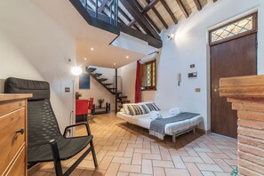 A cozy room with a bed, a chair, a desk, and a staircase leading to an upper level.