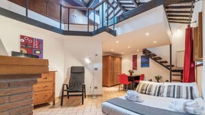 A modern hotel room with a bed, a desk, a chair, and a staircase leading to an upper level. - Amazing studio in Campo de' Fiori - Air Conditioning - Free Wi-Fi (Rome)