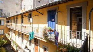 A yellow building with a balcony, a wooden door, and a window with a curtain. - Amazing studio in Campo de' Fiori - Air Conditioning - Free Wi-Fi (Rome)