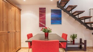 A dining area with a wooden cabinet, a table with red chairs, and a staircase with wooden steps. - Amazing studio in Campo de' Fiori - Air Conditioning - Free Wi-Fi (Rome)