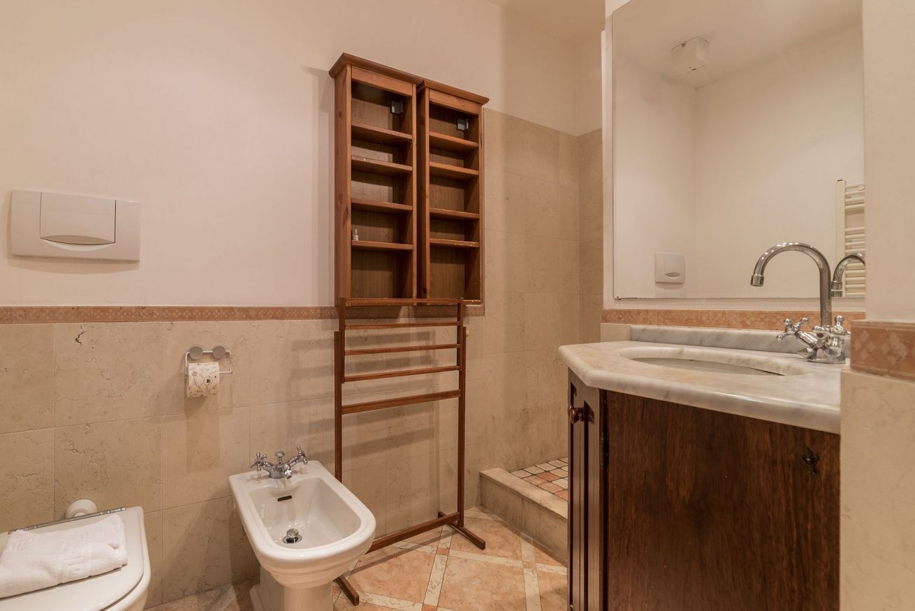 Un bagno con bidet, lavandino, specchio e un mobiletto in legno.