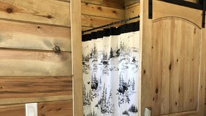 Una habitación de madera con una puerta corredera y cortina con motivos de bosque.