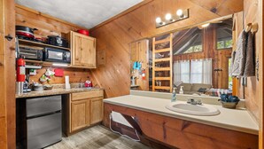 Eine holzgetäfelte Küchenzeile mit Kühlschrank, Mikrowelle und Herd.