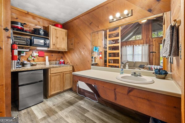 Una cocina tipo cabaña de madera con refrigerador, microondas y estufa.