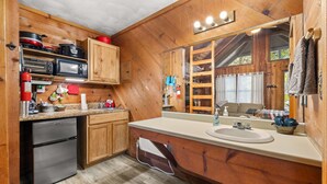 Una cocina tipo cabaña de madera con refrigerador, microondas y estufa.
