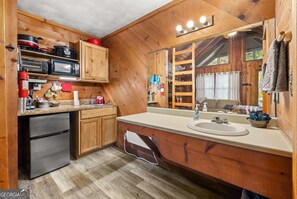 Eine holzgetäfelte Küchenzeile mit Kühlschrank, Mikrowelle und Herd.
