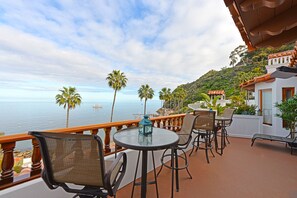 Enjoy ocean views from this balcony with a round table and comfortable seating.