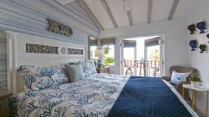 A bedroom with a bed, a nightstand, a window with a view, and a door leading to an outdoor area. - H890: Breathtaking ocean front villa, 2 Fireplaces, Cart, King Bed, VIEWS (Avalon)
