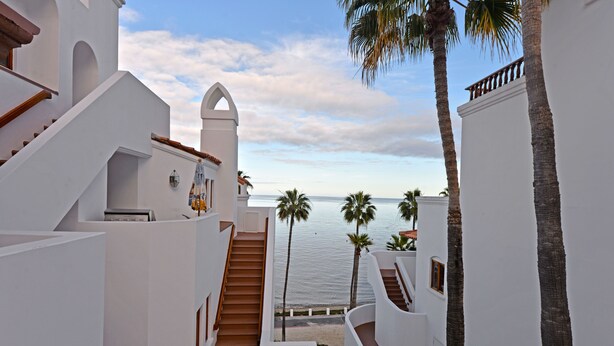 A white building with a staircase leading to a balcony overlooking the sea. - H890: Breathtaking ocean front villa, 2 Fireplaces, Cart, King Bed, VIEWS (Avalon)
