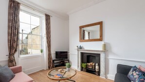 A living room with a fireplace, a television, and a sofa. - Garden maisonette in Bath city centre (Bath)