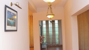 A hallway with a chandelier, a framed picture on the wall, and a patterned rug on the floor. - Shawnze House (Islamabad)