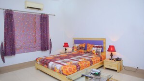 A bedroom with a bed, two bedside tables, a nightstand, a TV, and a curtain. - Shawnze House (Islamabad)