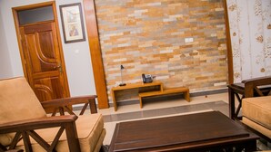 Una sala de estar con puerta de madera, pared de piedra, un banco y una mesa de centro.