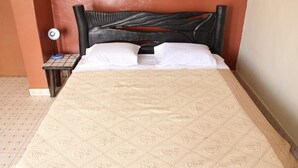 A bed with a floral-patterned mattress, a black headboard, and white pillows. - Joy Guesthouse (Kigali)