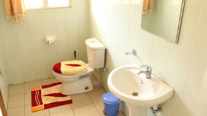A bathroom with a toilet, sink, and a window with curtains. - Joy Guesthouse (Kigali)