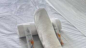 Una cama bien hecha con una colcha blanca y dos toallas enrolladas con estampado de jirafa.