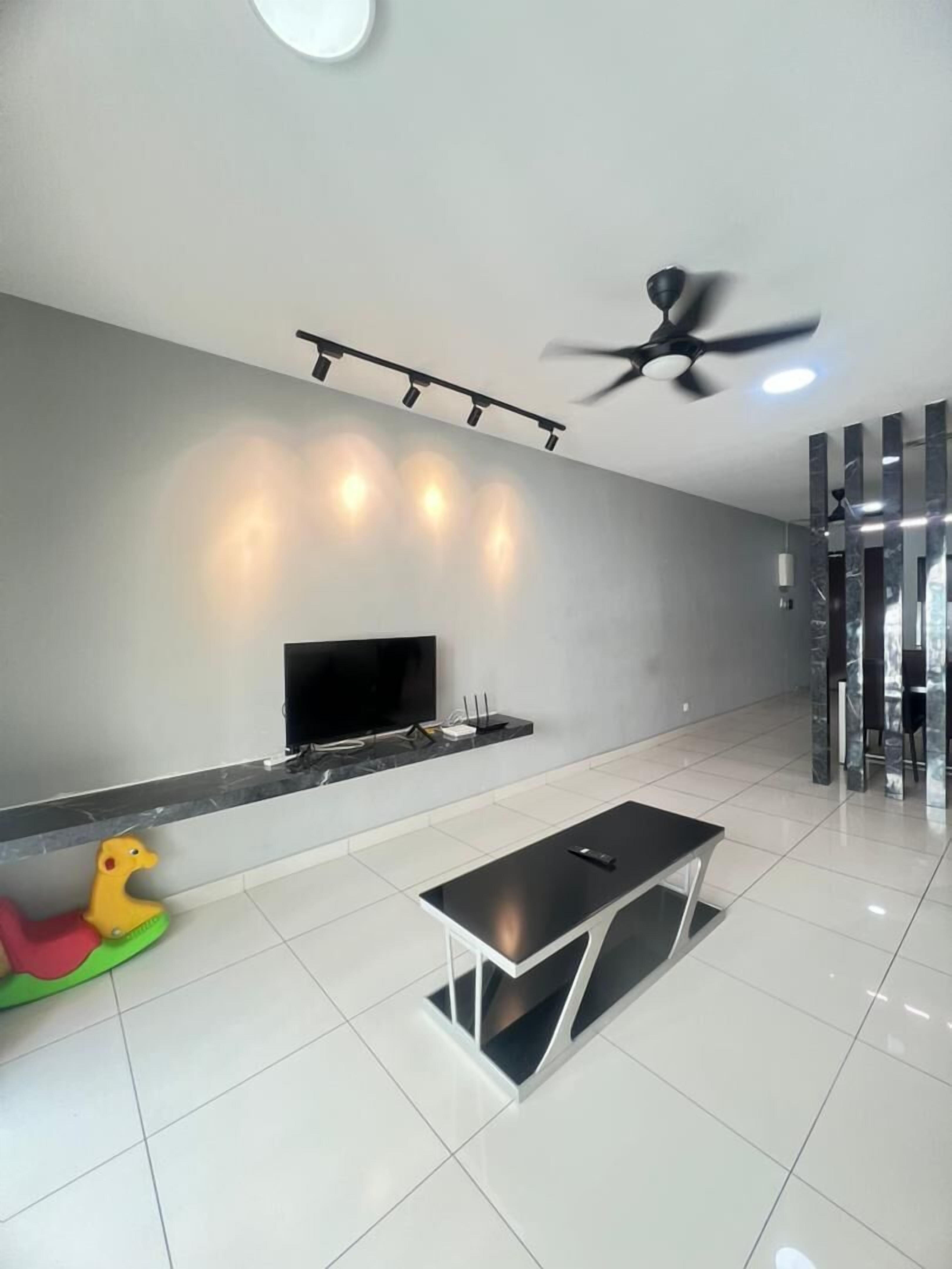 Una sala de estar moderna con un televisor de pantalla plana, ventilador de techo y un comedor con mesa y sillas.