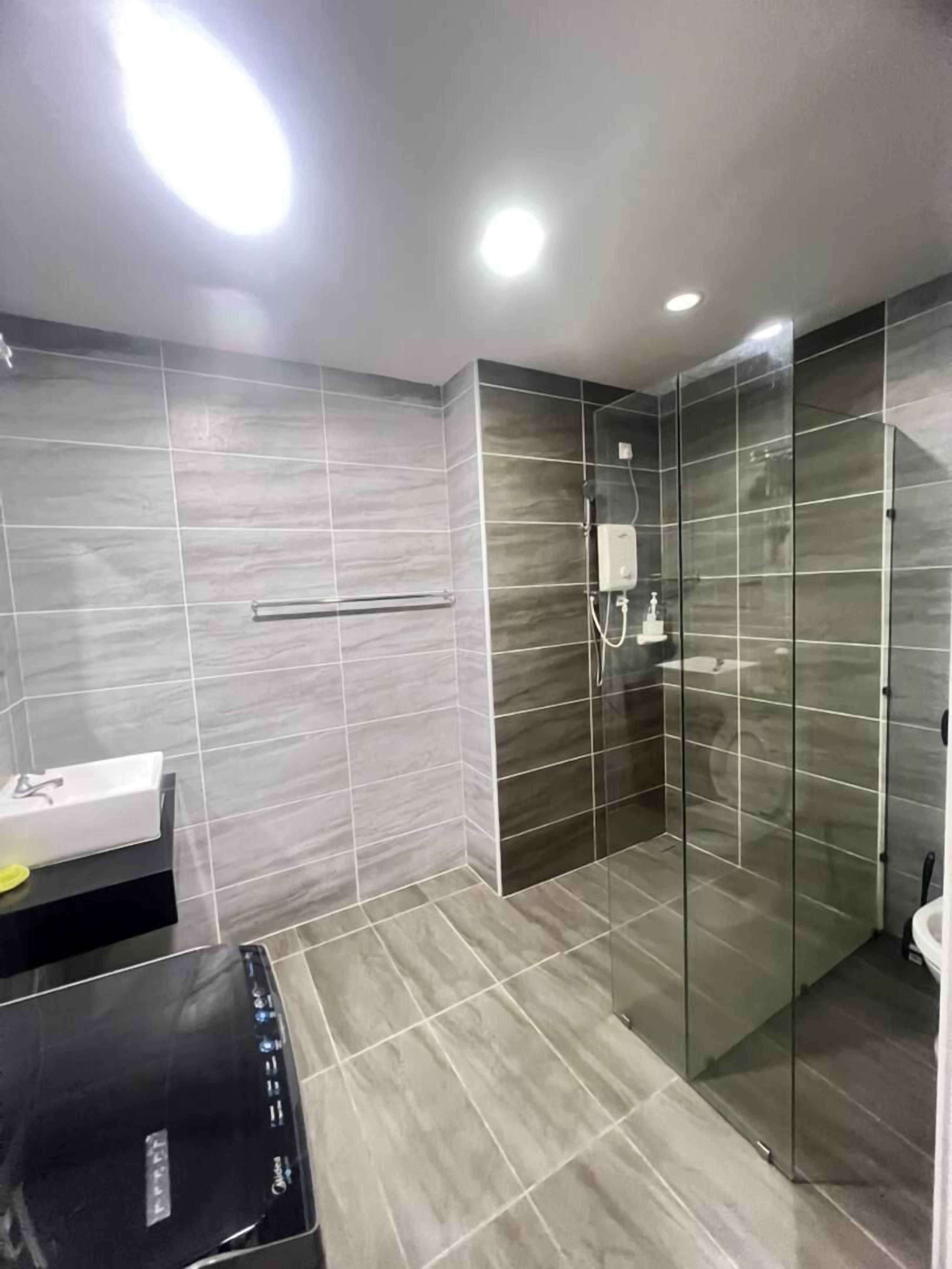 A modern bathroom with a glass shower enclosure, a vanity with a sink, and a black cabinet.