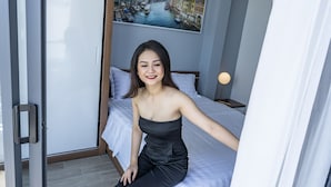 A room with a bed, a nightstand, a lamp, and a painting of a cityscape. - 7S Hotel Hoang Anh & Apartment (Nam Nha Trang)