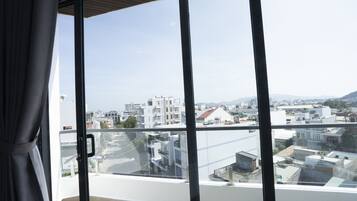 A balcony with a city view, large windows, and a curtain.