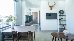 A modern living room with a dining area, a mounted deer head decoration, a flat-screen TV, and a bookshelf. - 7S Hotel Hoang Anh & Apartment (Nam Nha Trang)