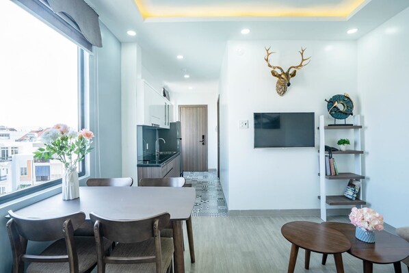 Uma sala de estar moderna com área de jantar, uma decoração de cabeça de veado montada, uma televisão de tela plana e uma estante.