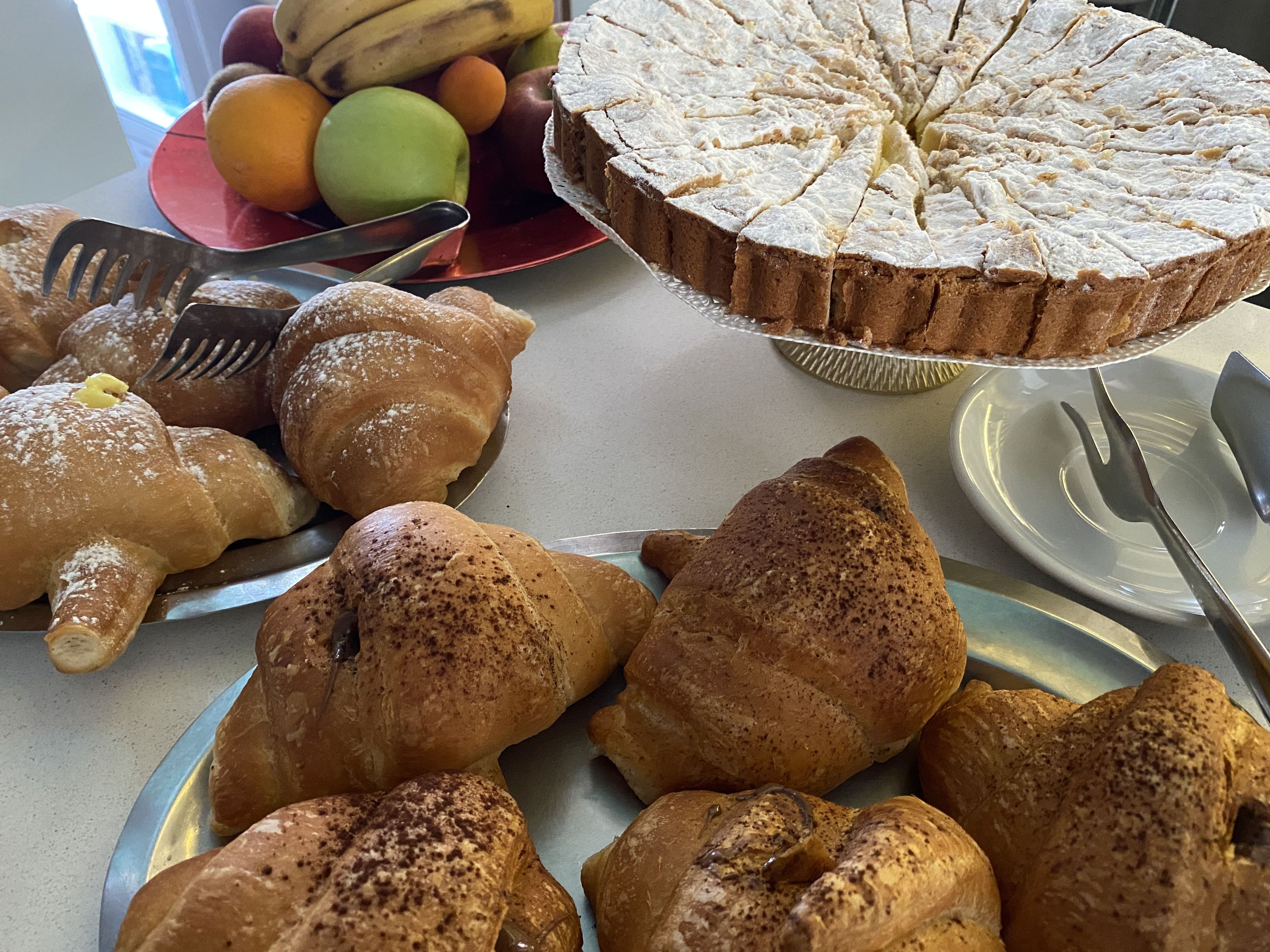 A table with various pastries and a fruit bowl.