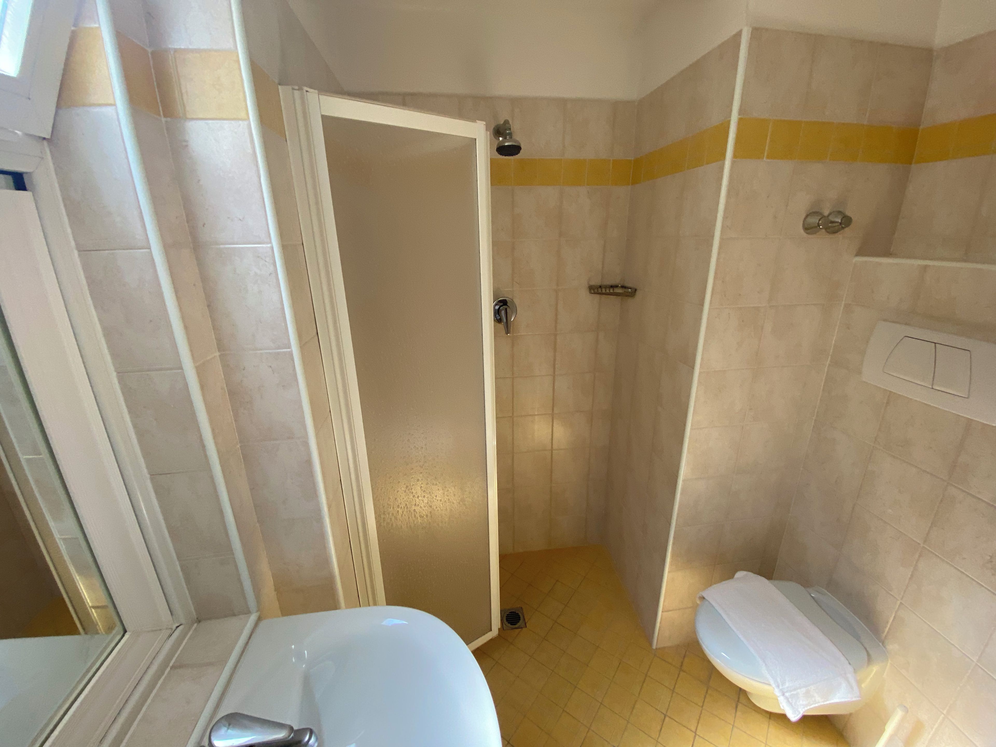 A bathroom with a shower, toilet, and sink.