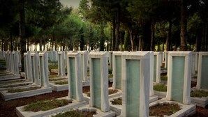 Un cementerio con lápidas blancas y uniformes dispuestas en filas.
