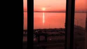 Un atardecer sobre aguas tranquilas, visto a través de marcos de ventana.