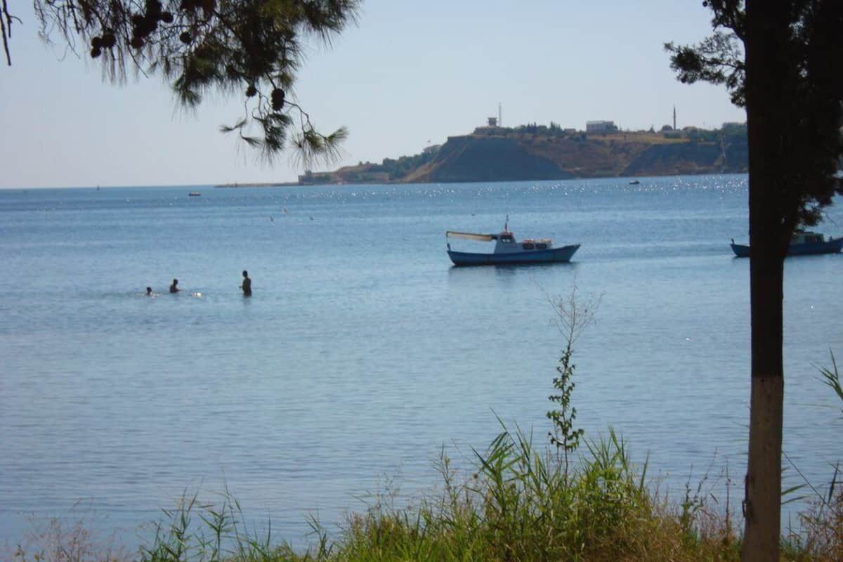 A calm body of water with boats and a distant hill.
