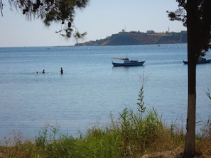A calm body of water with boats and a distant hill.