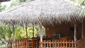 Uma cabana com telhado de palha, móveis de madeira e plantas em vasos.