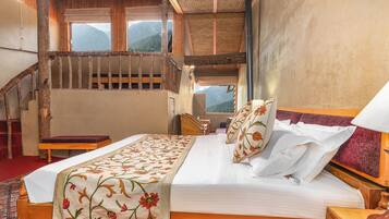 A bedroom with a wooden bed, a red carpet, a wooden chair, a nightstand, and a staircase with a wooden railing.
