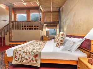 A bedroom with a wooden bed, a red carpet, a wooden chair, a nightstand, and a staircase with a wooden railing. - Pahalgam hotel (Anantnag)