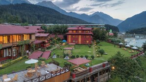 A hotel with multiple buildings, outdoor seating areas, and a river view. - Pahalgam hotel (Anantnag)