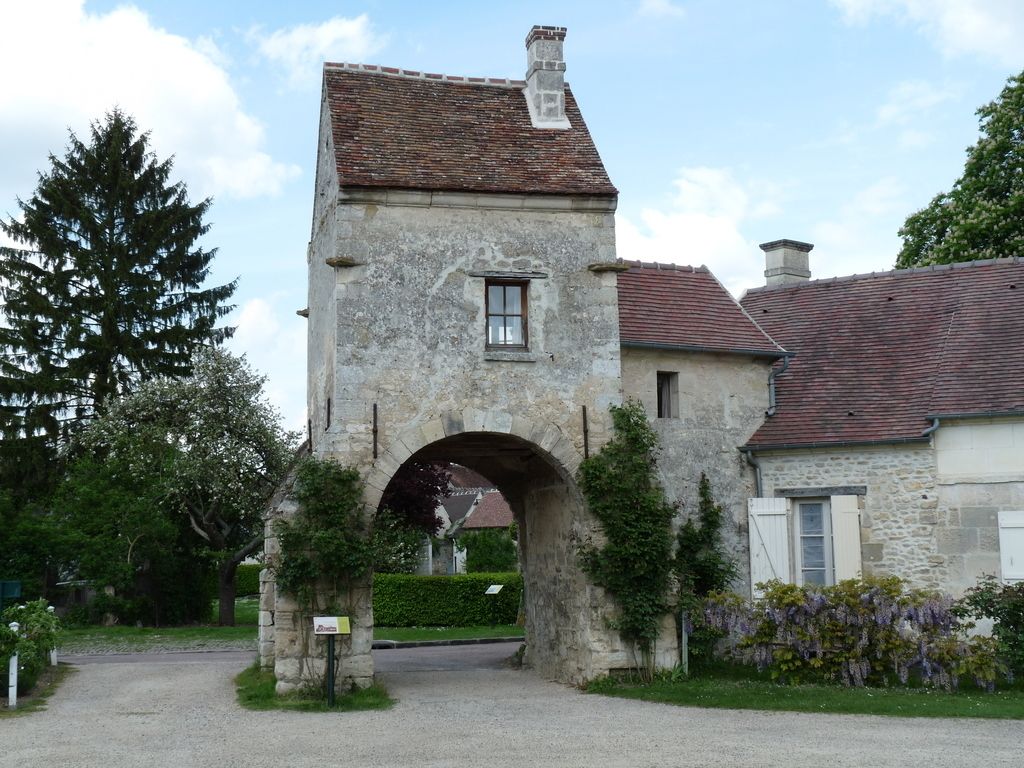 A stone building with a central archway, a small window, and a chimney.
